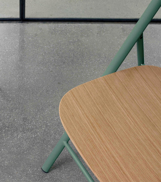 Joe wooden chair with green metal legs on a concrete floor