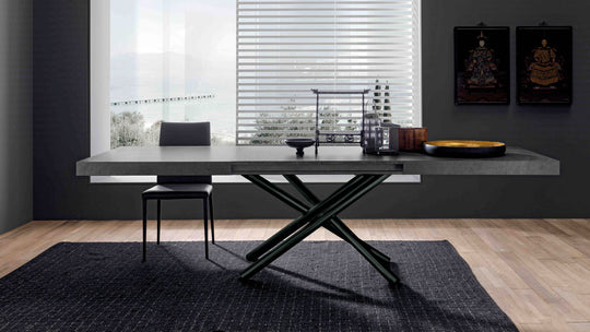 London modern extendable dining table with black base in a room with large windows and dark walls.