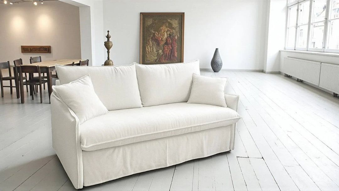 White Shabby chic sofa in a bright living room with a dining area in the background