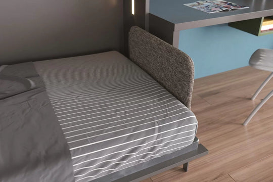 Nest single horizontal wall bed. Bed with striped mattress in a room with a desk and chair.