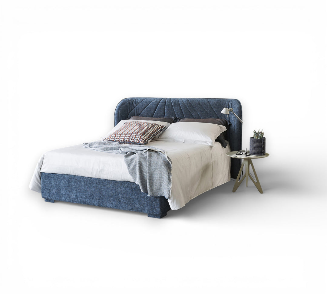 Victoria ottoman storage bed blue upholstered bed with white bedding and a side table in a minimalistic room.